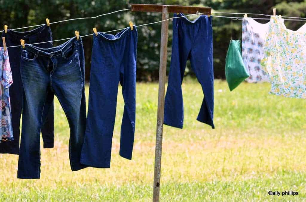 1940s WOMAN HANGING LAUNDRY ON CLOTHESLINE OUTDOORS - Stock Photo