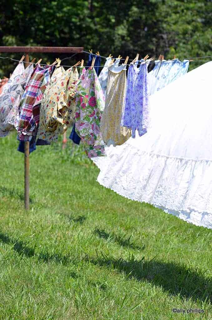 1940s WOMAN HANGING LAUNDRY ON CLOTHESLINE OUTDOORS - Stock Photo